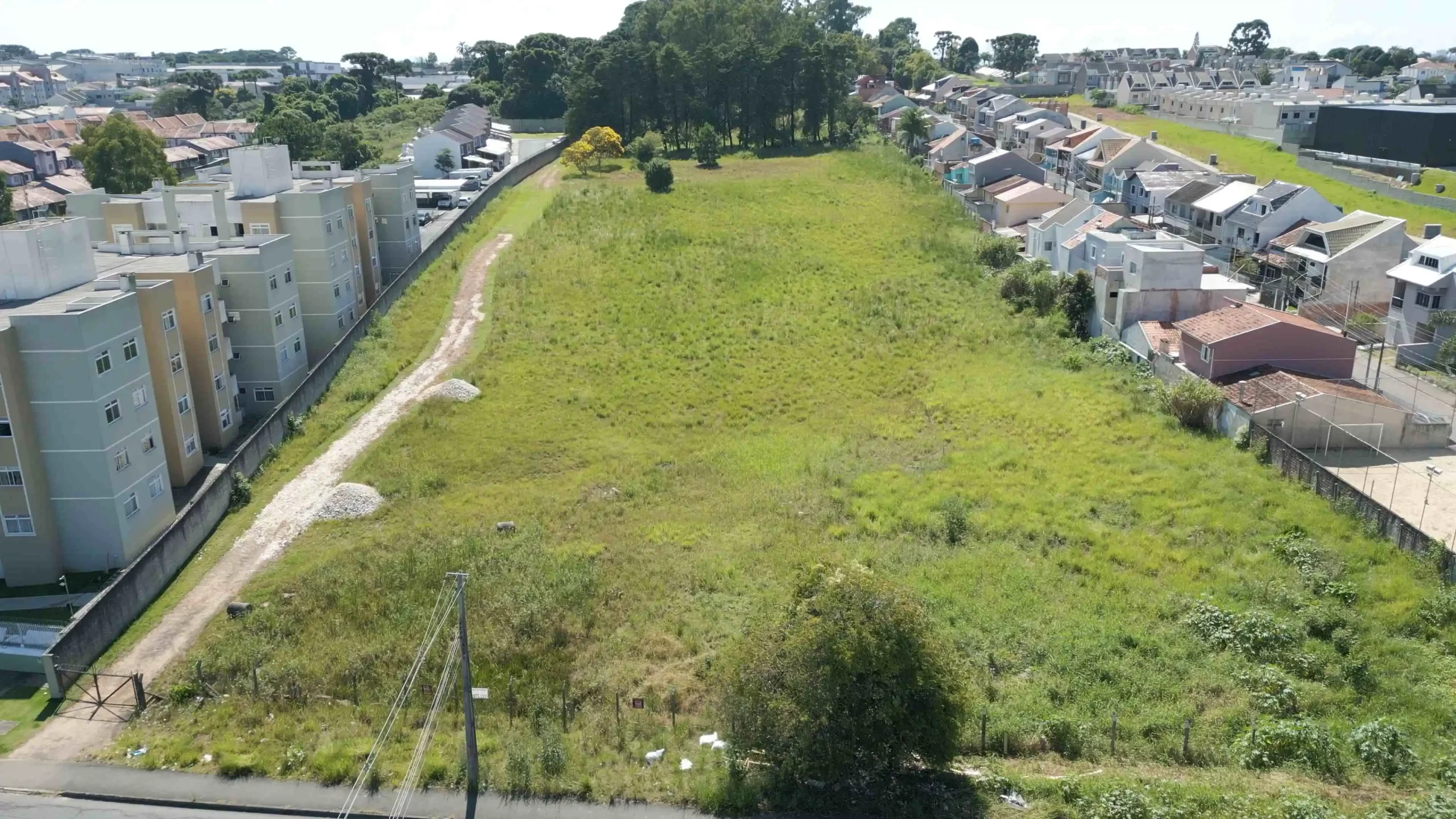Terreno vazio em área urbana residencial, pronto para construção, ilustrando o início do processo de construir em terreno próprio com planejamento e infraestrutura.