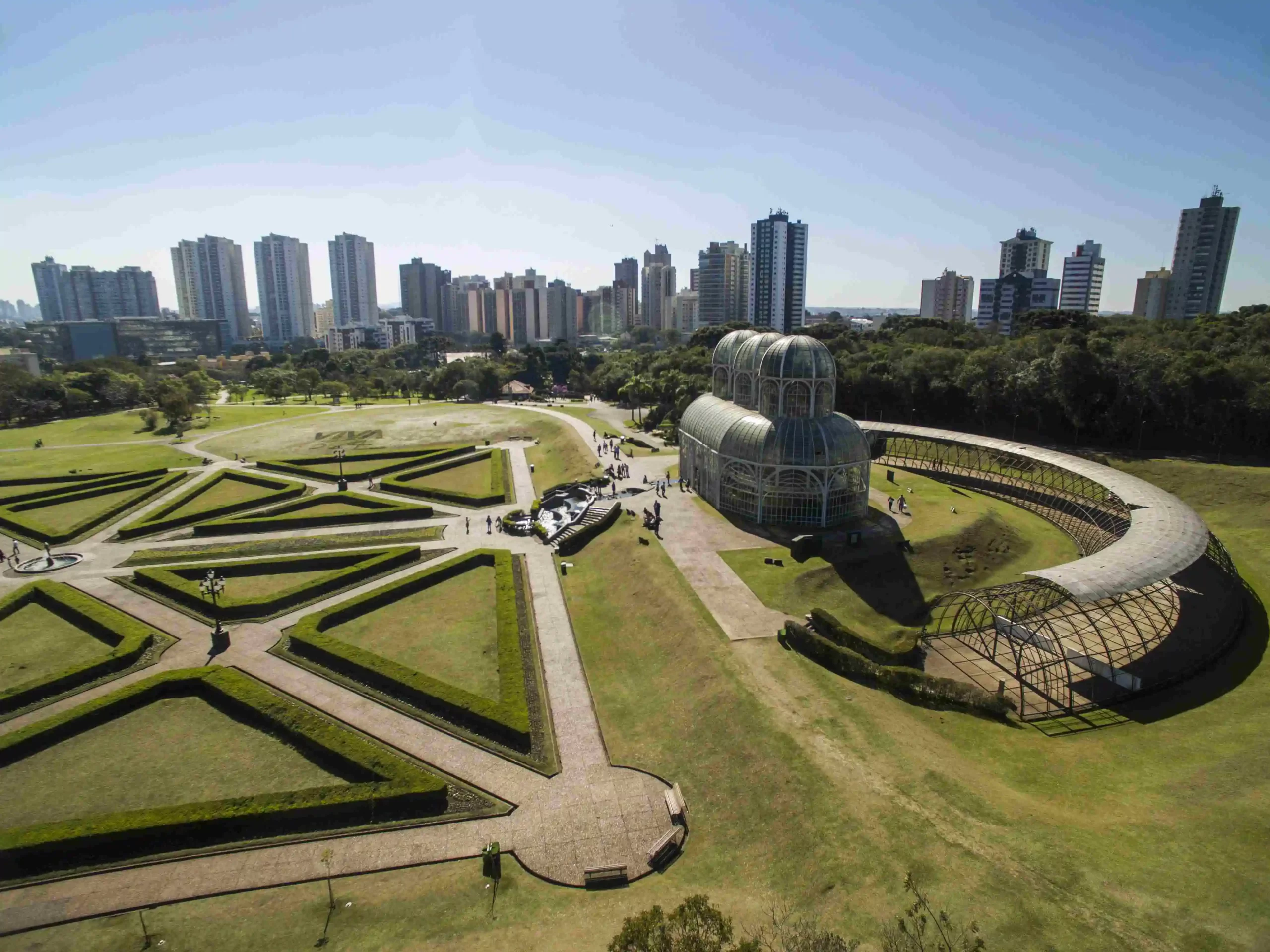 Jardim Botânico de Curitiba com paisagismo geométrico e estufa moderna, refletindo o estilo de vida inteligente e prático de quem escolhe viver na cidade.